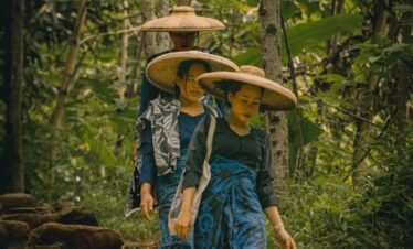 A couple of people walking down a dirt road