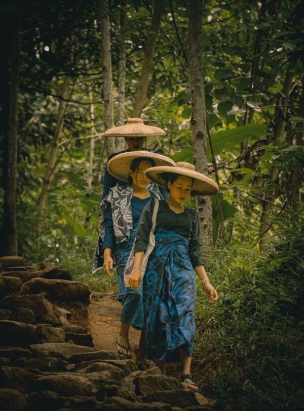 A couple of people walking down a dirt road