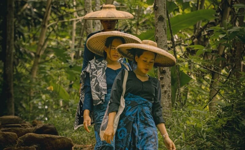 A couple of people walking down a dirt road