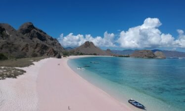 a boat is sitting on a pink beach