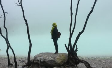 a person standing on a rock next to a body of water