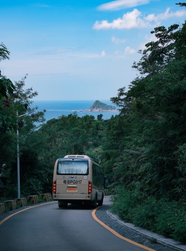 A bus drives down a winding road to the sea.