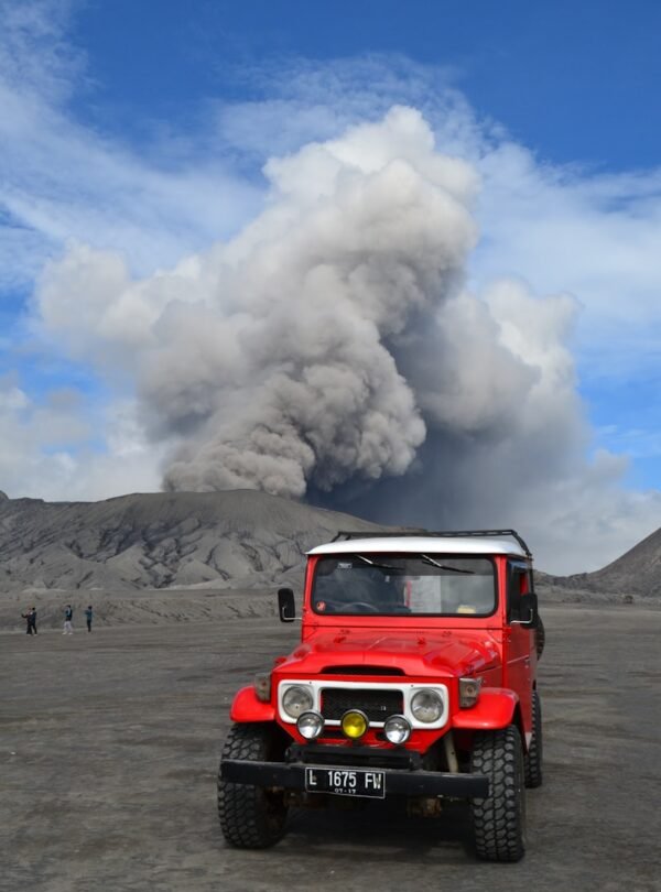red suv on brown sand under white clouds and blue sky during daytime