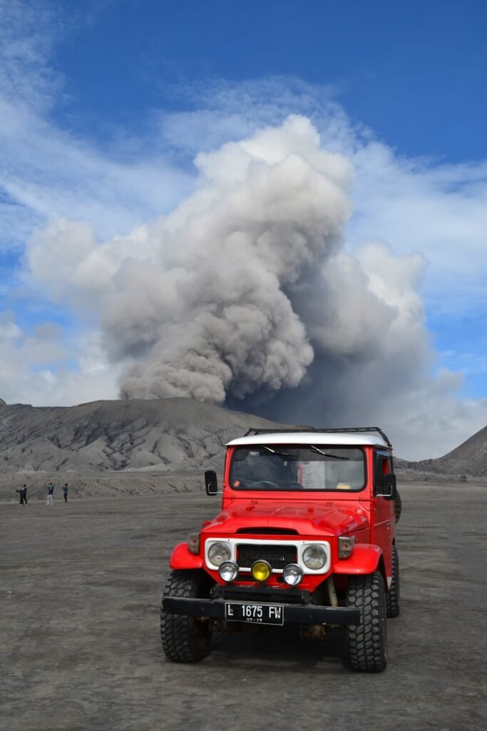 red suv on brown sand under white clouds and blue sky during daytime