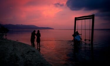 silhouette of 2 women standing on beach during sunset