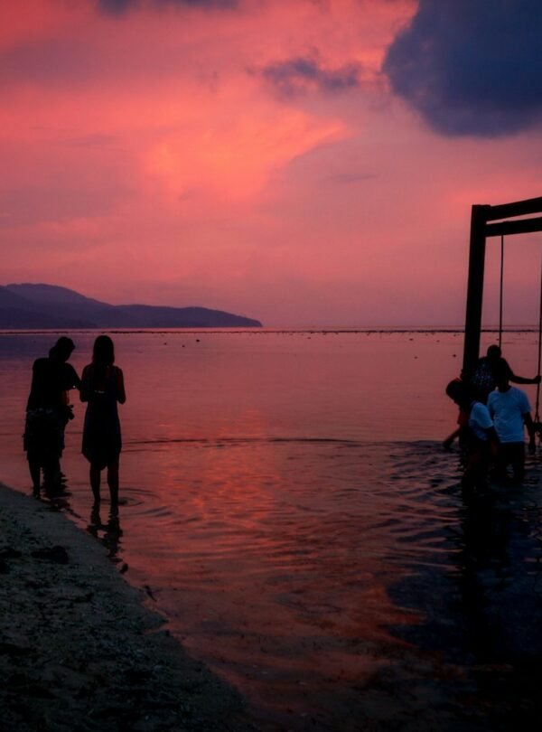 silhouette of 2 women standing on beach during sunset