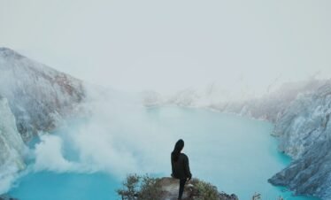 a person sitting on a cliff overlooking a body of water