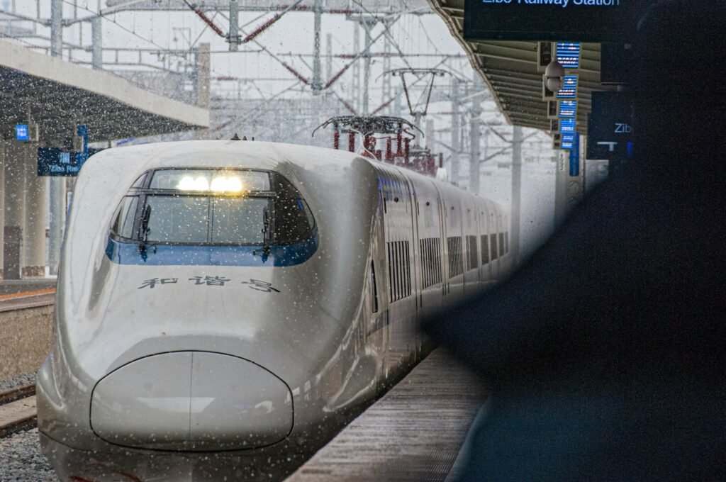 a white train traveling down train tracks next to a loading platform