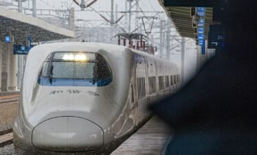 a white train traveling down train tracks next to a loading platform
