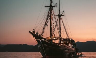 brown sail boat on sea during sunset
