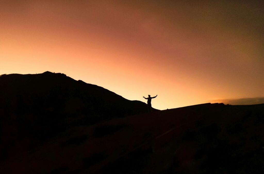 a person standing on top of a hill at sunset