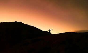 a person standing on top of a hill at sunset